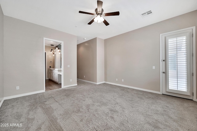 unfurnished bedroom featuring visible vents, connected bathroom, baseboards, carpet, and ceiling fan