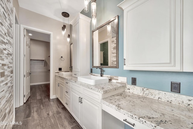 bathroom featuring double vanity, wood finished floors, baseboards, and a sink