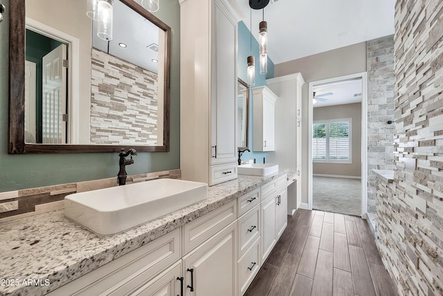 full bath with double vanity, wood finish floors, ceiling fan, and a sink