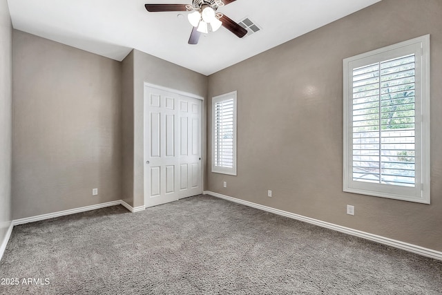 unfurnished bedroom featuring baseboards, visible vents, ceiling fan, a closet, and carpet flooring