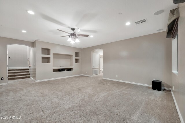 unfurnished living room featuring visible vents, arched walkways, carpet floors, and ceiling fan