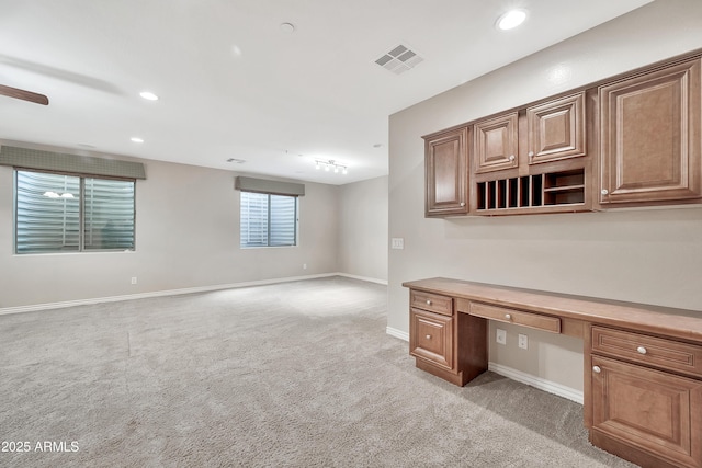 unfurnished office featuring visible vents, built in desk, recessed lighting, baseboards, and light colored carpet