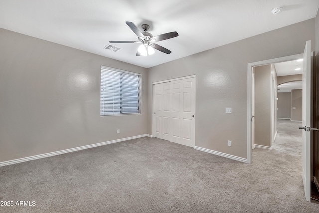 unfurnished bedroom with visible vents, baseboards, a closet, carpet flooring, and arched walkways