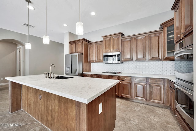 kitchen featuring visible vents, arched walkways, a sink, decorative backsplash, and appliances with stainless steel finishes