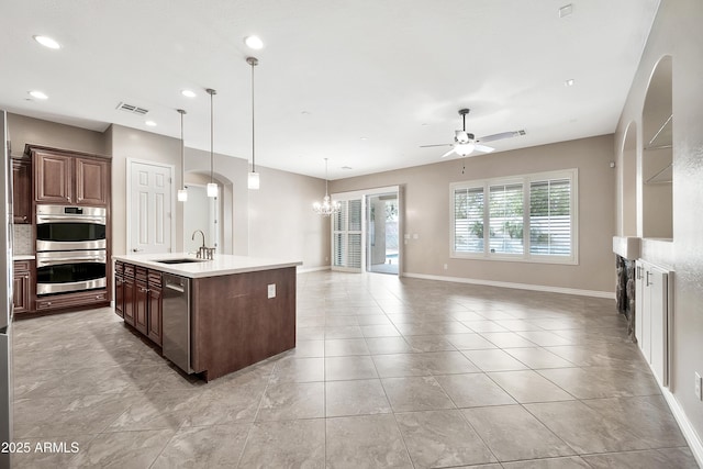 kitchen featuring visible vents, open floor plan, light countertops, ceiling fan with notable chandelier, and stainless steel appliances