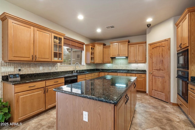 kitchen featuring a center island, a sink, visible vents, black appliances, and tasteful backsplash