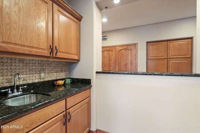 kitchen with dark stone counters, tasteful backsplash, brown cabinets, and a sink