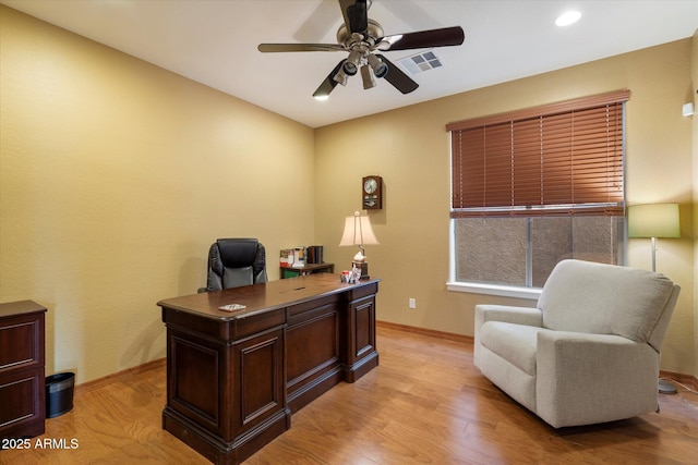 home office featuring baseboards, light wood finished floors, ceiling fan, and visible vents