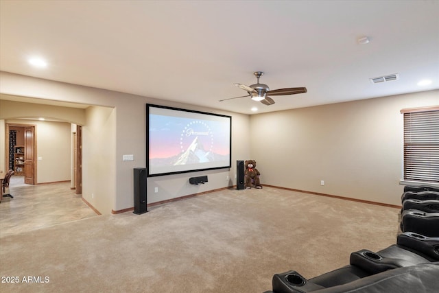 cinema room featuring a ceiling fan, baseboards, visible vents, arched walkways, and light carpet