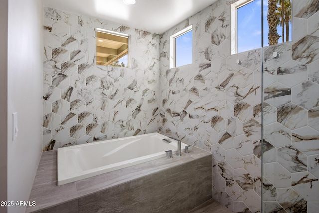 bathroom with a relaxing tiled tub and tile walls