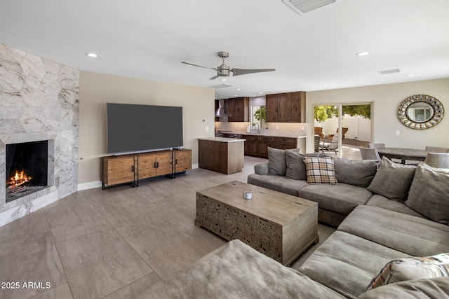 living room featuring a fireplace, ceiling fan, and sink