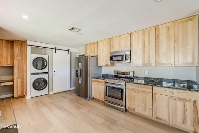 3138 N 82nd Pl, Scottsdale, AZ 85251 - kitchen with stacked washer and clothes dryer, light wood-style floors, visible vents, appliances with stainless steel finishes, and light brown cabinetry