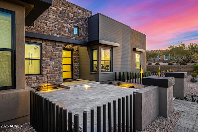 exterior space featuring stone siding and a fenced front yard