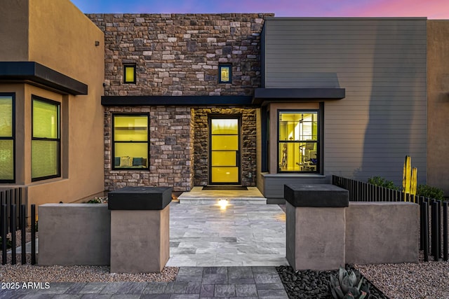 exterior entry at dusk featuring stone siding