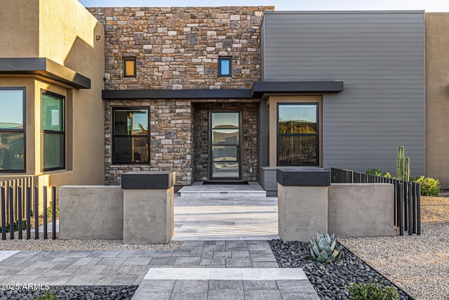 entrance to property with stone siding and fence