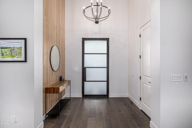 foyer featuring dark wood-style floors, baseboards, and a notable chandelier