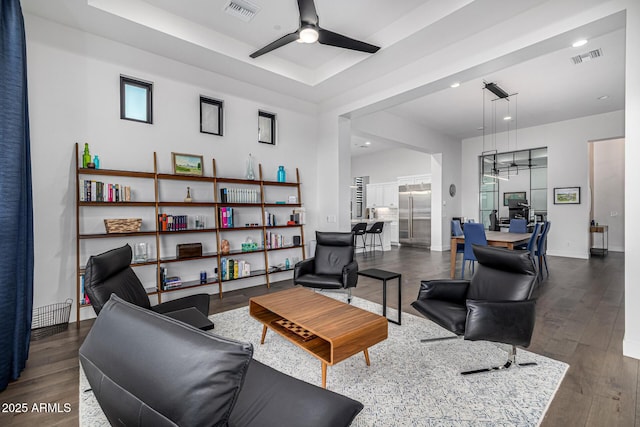 living room with wood finished floors, visible vents, and a ceiling fan