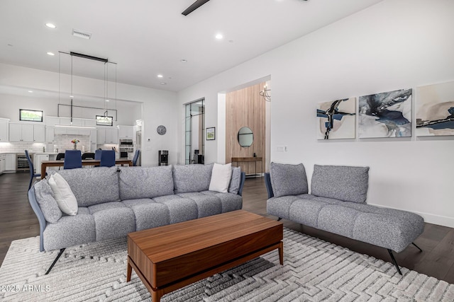 living area with baseboards, visible vents, dark wood finished floors, and recessed lighting