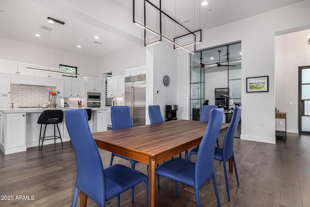 dining space with dark wood finished floors, recessed lighting, visible vents, a towering ceiling, and baseboards