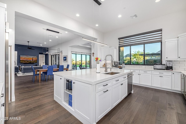 kitchen featuring dark wood-type flooring, open floor plan, a sink, and stainless steel dishwasher