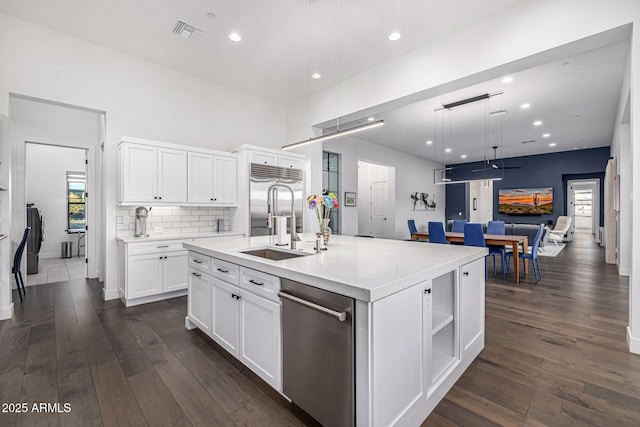 kitchen with dark wood finished floors, visible vents, open floor plan, white cabinetry, and a sink