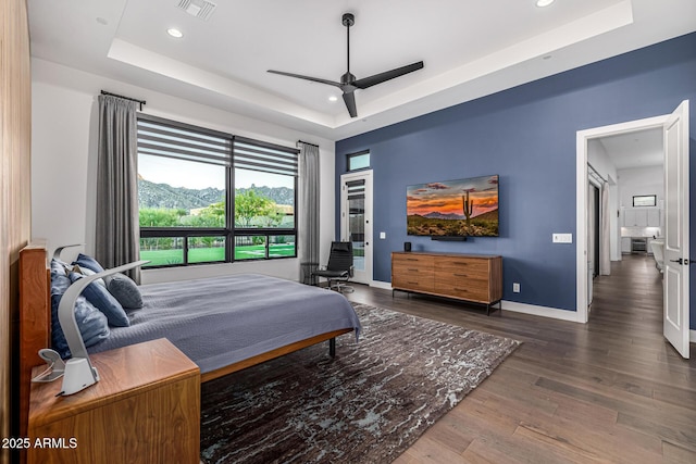 bedroom with baseboards, visible vents, a raised ceiling, wood finished floors, and recessed lighting