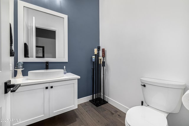 half bathroom featuring vanity, wood finished floors, toilet, and baseboards