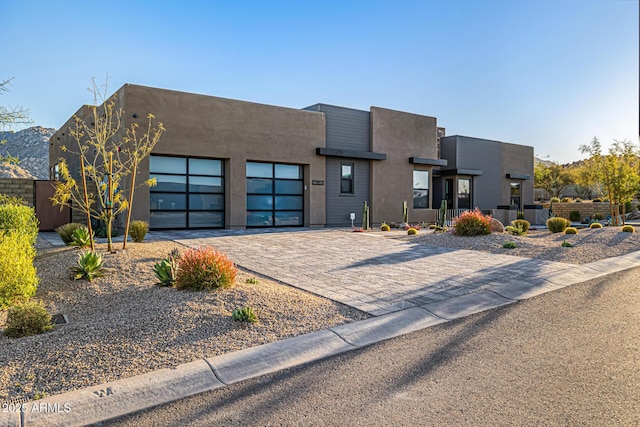 view of front facade featuring an attached garage, decorative driveway, and stucco siding