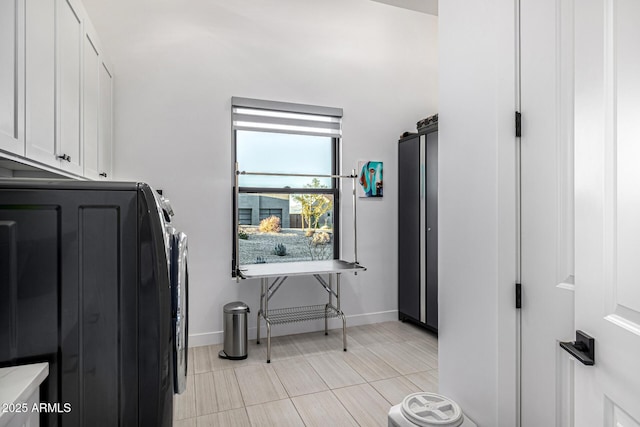 washroom with light tile patterned floors, washer and clothes dryer, cabinet space, and baseboards