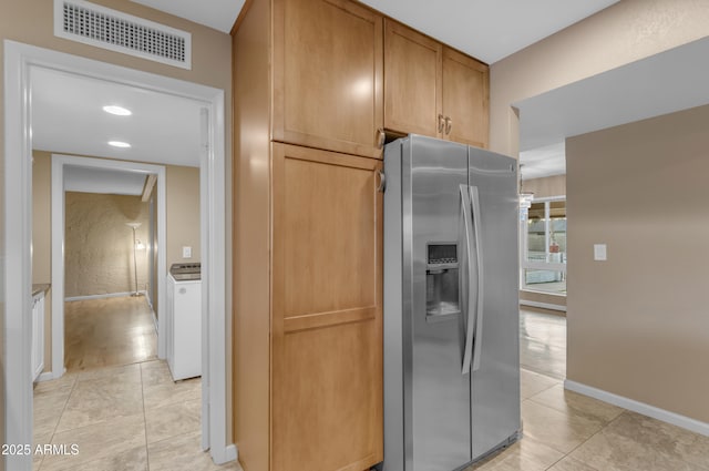 kitchen with light tile patterned flooring, stainless steel fridge with ice dispenser, and washer / dryer