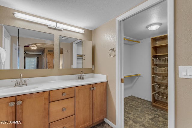 bathroom with ceiling fan, vanity, and a textured ceiling