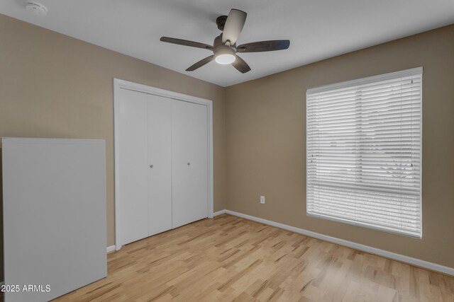 unfurnished bedroom featuring ceiling fan, light hardwood / wood-style floors, and a closet