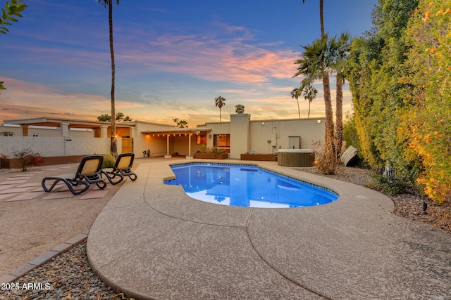 pool at dusk with a patio area and cooling unit