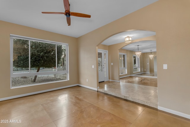 empty room with ceiling fan with notable chandelier