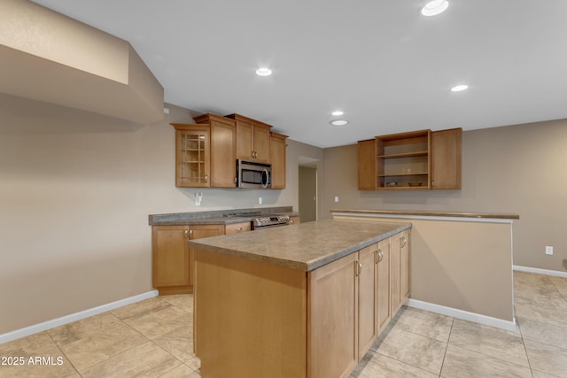 kitchen with appliances with stainless steel finishes, a kitchen island, and light tile patterned floors