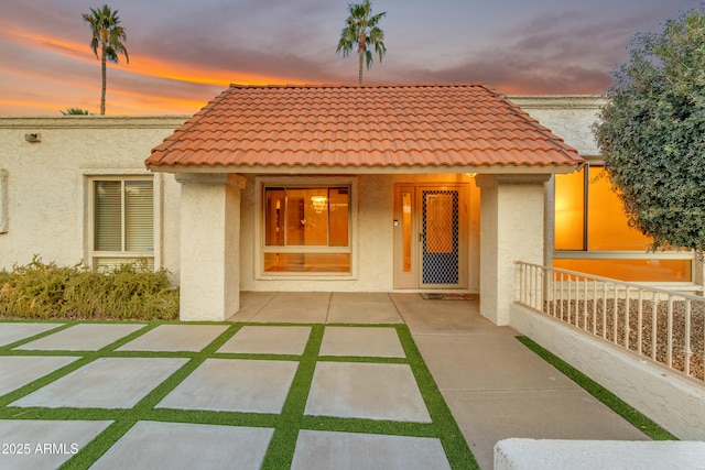 back house at dusk featuring a patio area