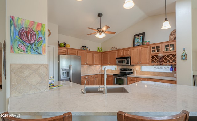 kitchen with sink, tasteful backsplash, vaulted ceiling, a breakfast bar, and appliances with stainless steel finishes