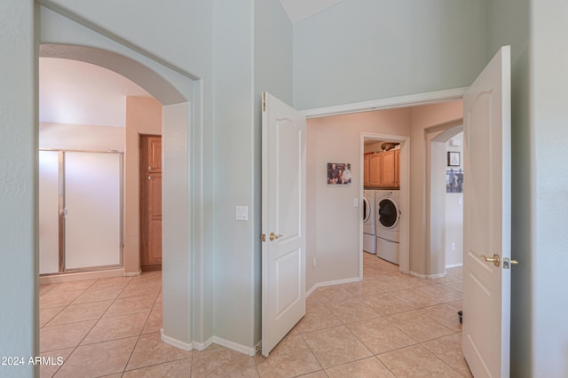 corridor featuring light tile patterned floors and washing machine and dryer