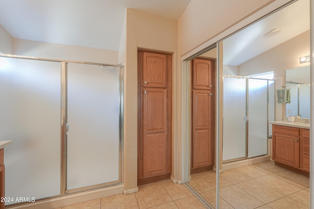 bathroom featuring tile patterned flooring, vanity, vaulted ceiling, and walk in shower