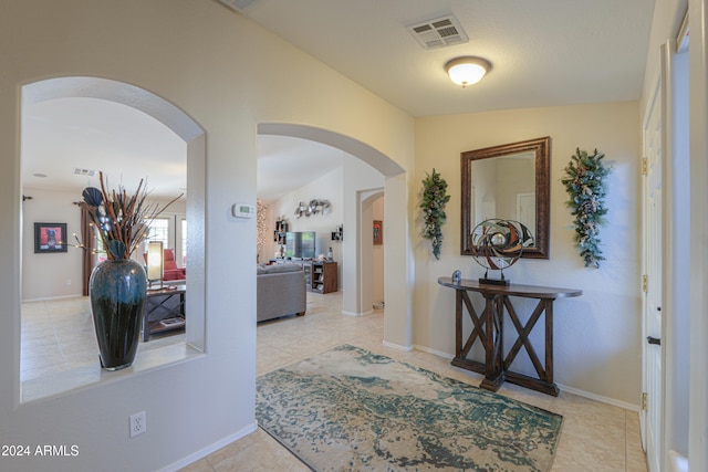 hallway with lofted ceiling and light tile patterned flooring