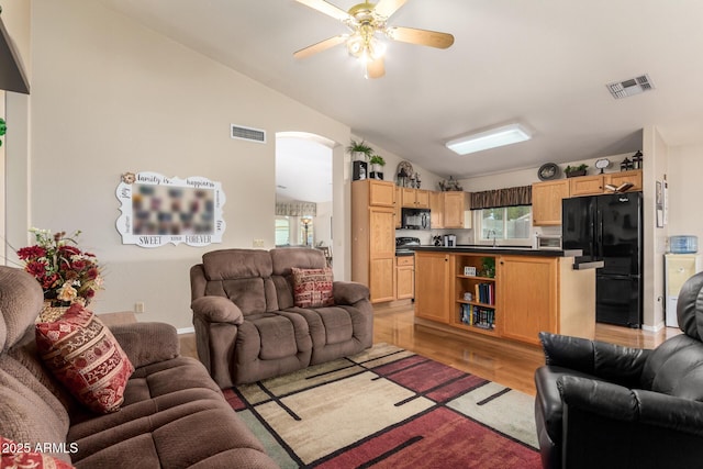 living room featuring ceiling fan, a healthy amount of sunlight, lofted ceiling, and light hardwood / wood-style flooring