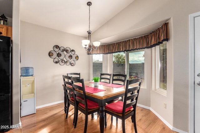 dining area featuring light hardwood / wood-style flooring, lofted ceiling, and a notable chandelier