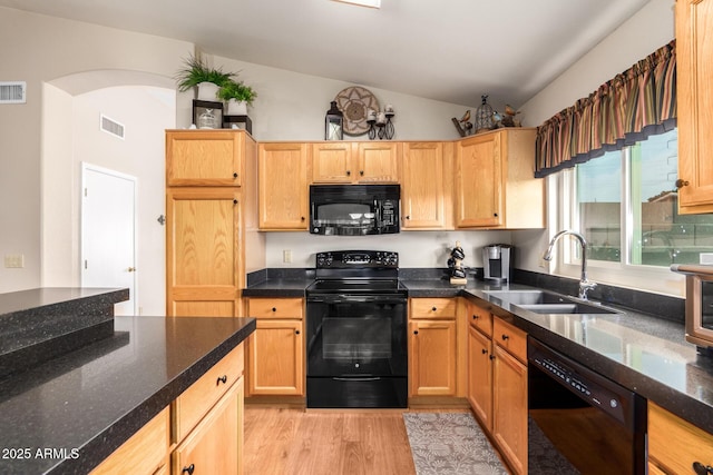 kitchen featuring black appliances, vaulted ceiling, sink, and light hardwood / wood-style flooring