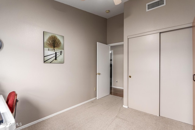 unfurnished bedroom with light colored carpet and a closet