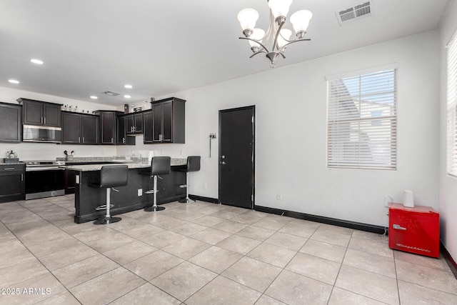 kitchen featuring appliances with stainless steel finishes, light tile patterned flooring, a chandelier, recessed lighting, and a kitchen bar