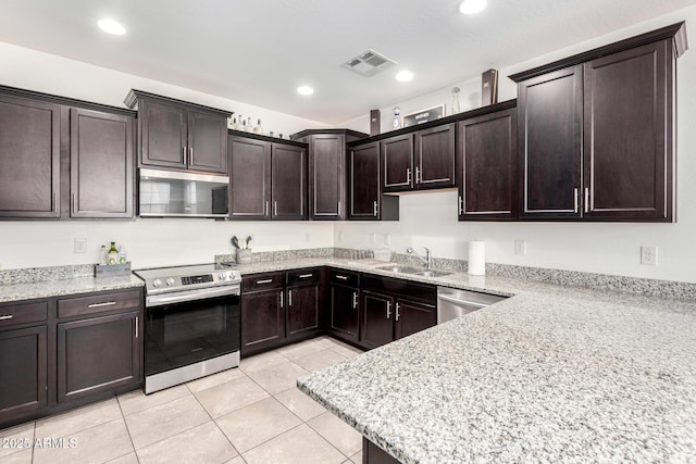 kitchen with appliances with stainless steel finishes, a sink, light tile patterned floors, dark brown cabinetry, and recessed lighting