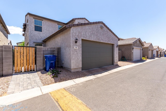 view of front of property featuring stucco siding, a gate, a garage, and fence