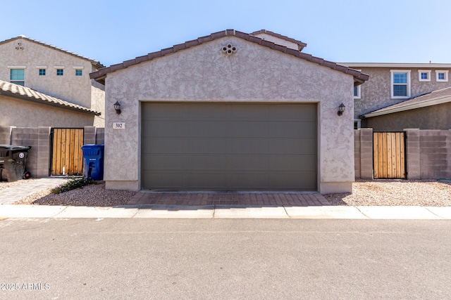 view of front of home featuring stucco siding, fence, and a gate