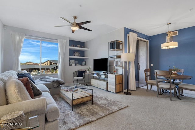 living room featuring ceiling fan, built in shelves, and carpet