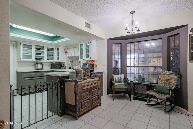 kitchen with sink, an inviting chandelier, light tile patterned flooring, a textured ceiling, and white cabinets